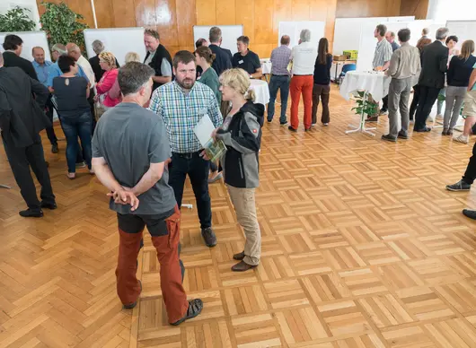 Personen unterhalten sich in Kleingruppen stehend.